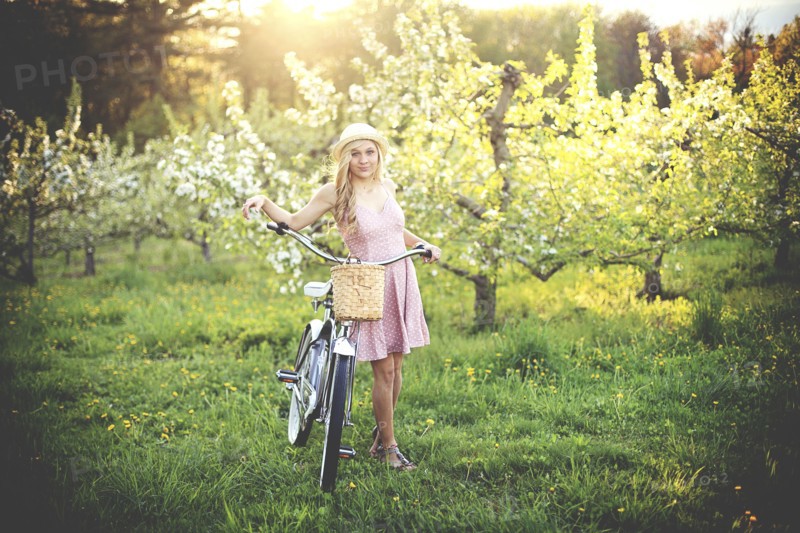 Woman pushing bicycle in rural field