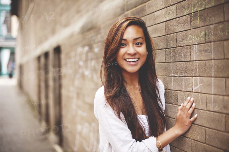 Woman standing at brick wall in city
