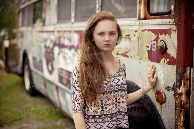 Caucasian teenage girl standing near dilapidated bus
