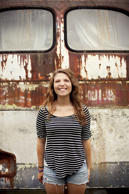 Smiling girl standing near dilapidated bus