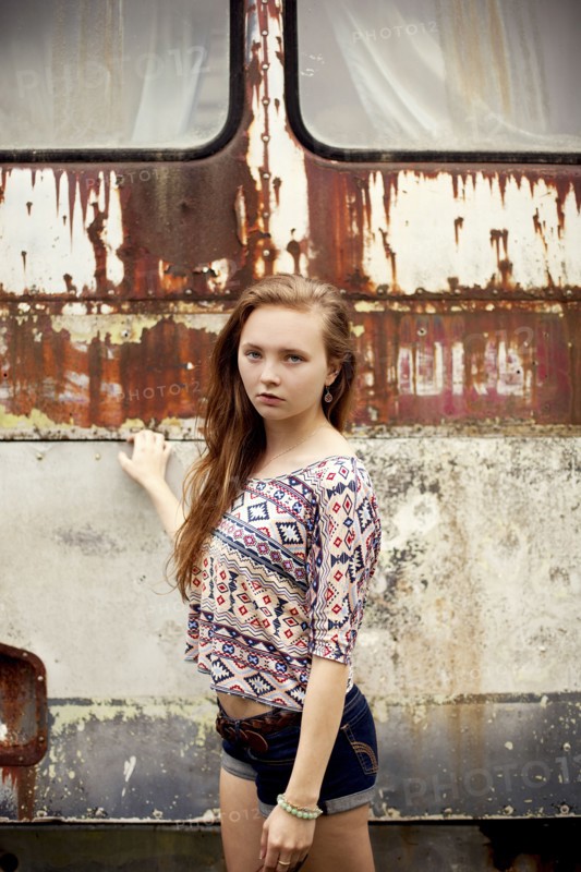 Caucasian girl standing near dilapidated bus