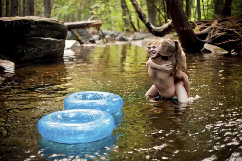 Man carrying girlfriend piggyback in forest river