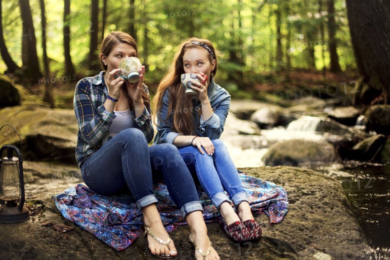 Girls drinking coffee on forest rock