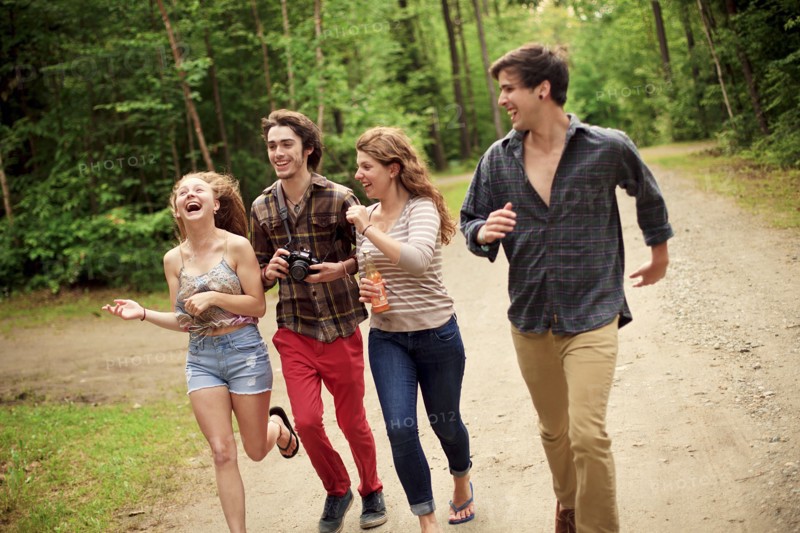 Friends running on dirt path in forest