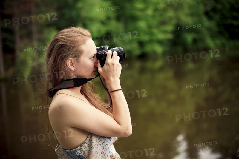 Caucasian teenage girl photographing lake