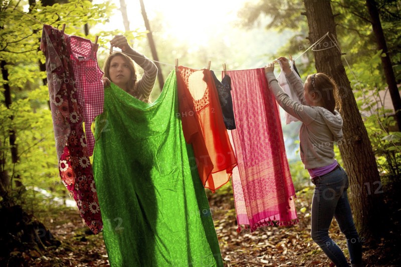 Girls hanging laundry on clothesline in forest
