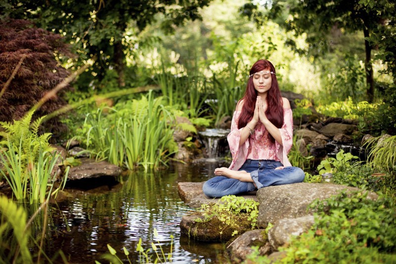 Girl meditating near rural creek