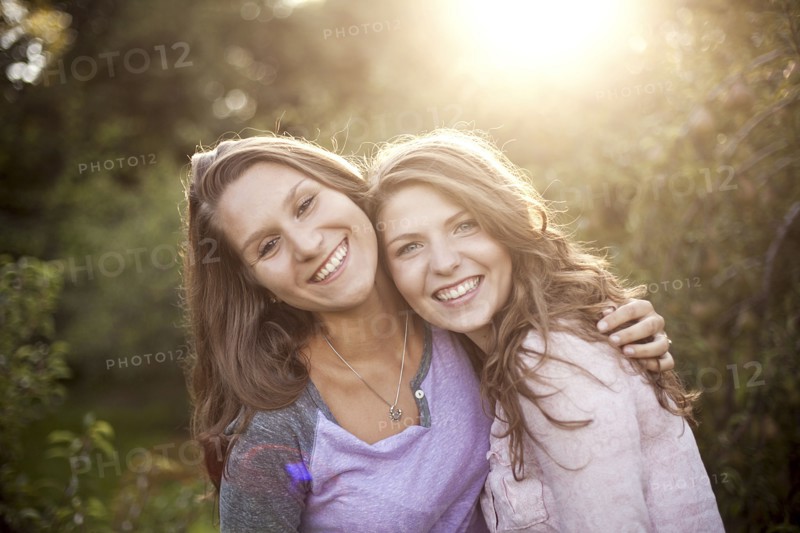 Smiling women hugging in rural field