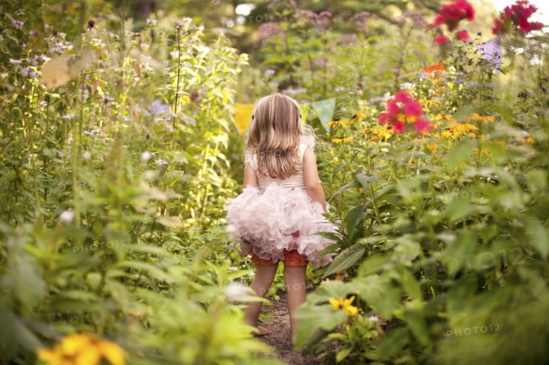Girl in frilly dress exploring tall flowers