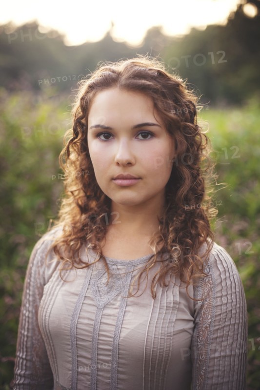 Serious woman standing in rural field