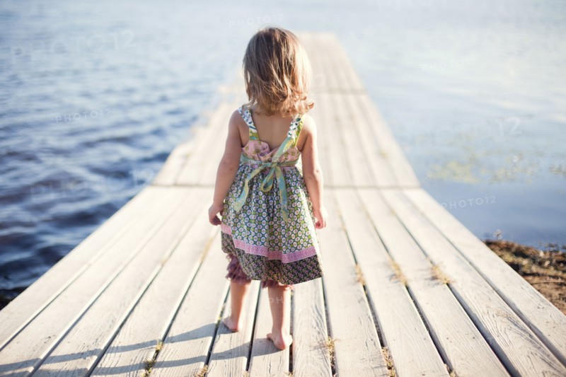 Girl walking on wooden dock over rural lake