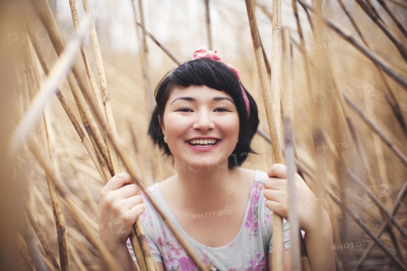 Smiling mixed race woman holding stalks in field