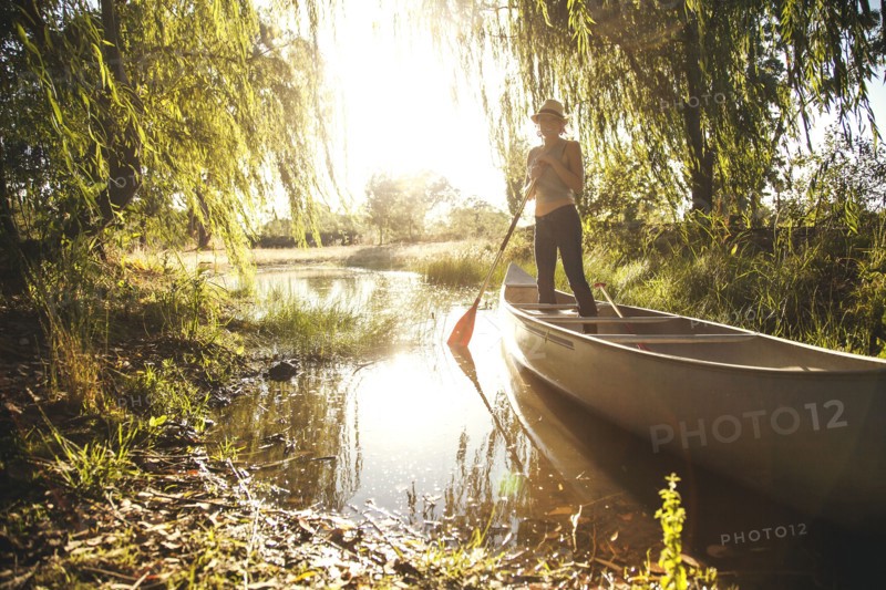 Caucasian woman rowing canoe in rural creek