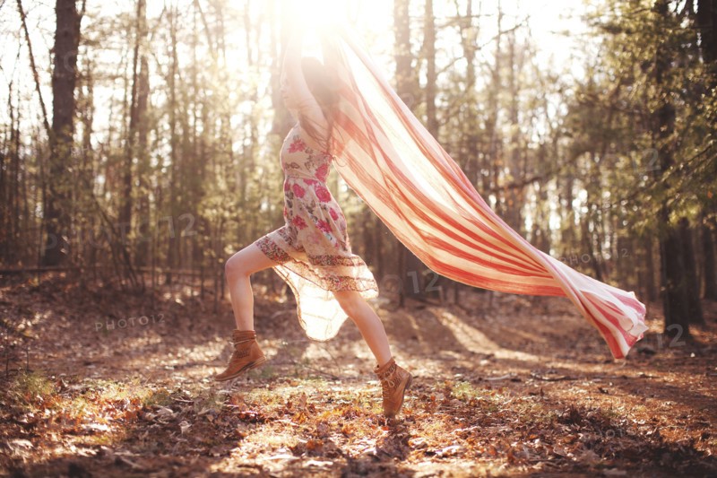 Hispanic woman running with scarf in forest
