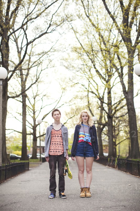 Caucasian couple standing in park with skateboard