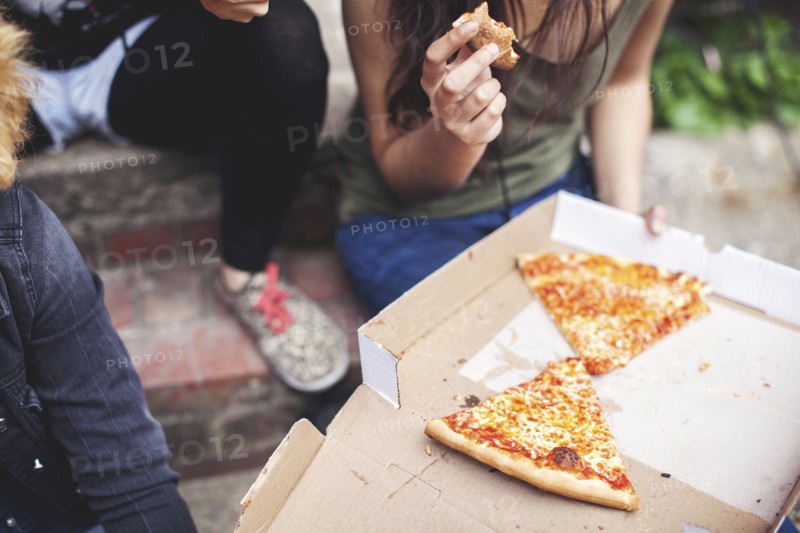 Women eating pizza on front steps