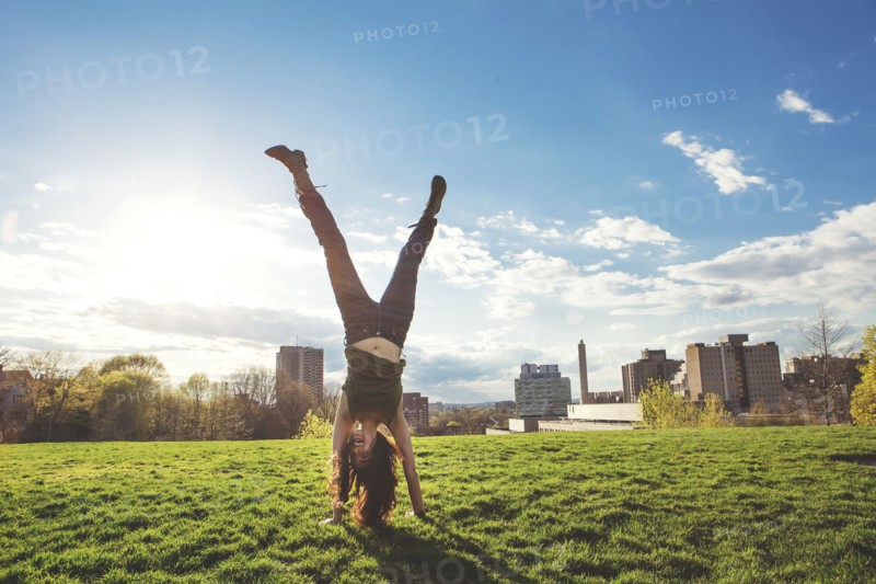 Caucasian woman doing handstand in urban park