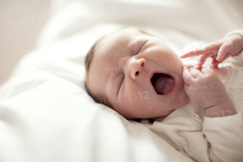 Caucasian baby girl yawning on bed