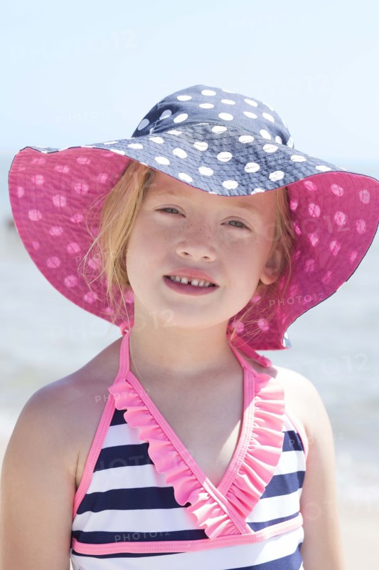Caucasian girl wearing sun hat and bathing suit on beach