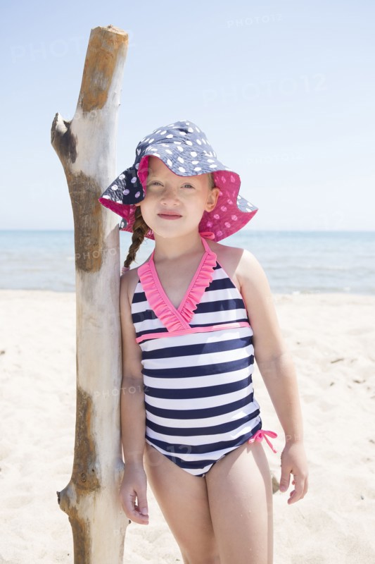 Caucasian girl leaning on wooden pole on beach