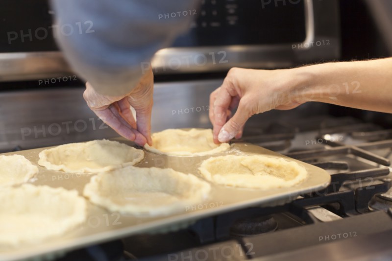 Close up of woman lining pie pans on stove