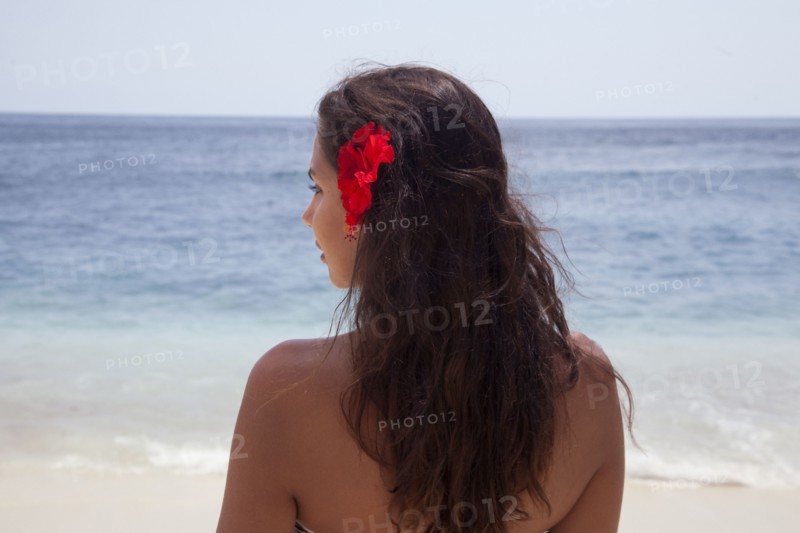 Rear view of woman wearing flower in her hair on beach