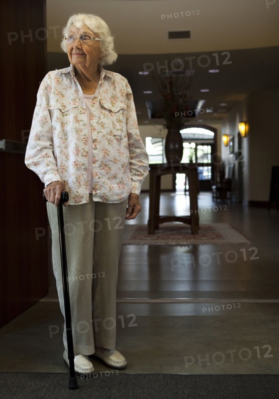 Older Caucasian woman standing with cane in retirement home