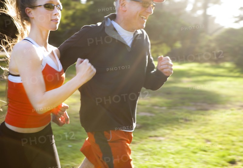 Caucasian man running with trainer in field