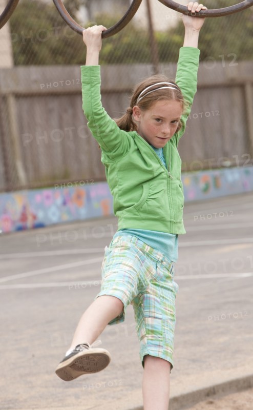 Caucasian girl playing on monkey bars at playground
