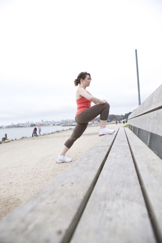 Caucasian woman stretching on beach bench