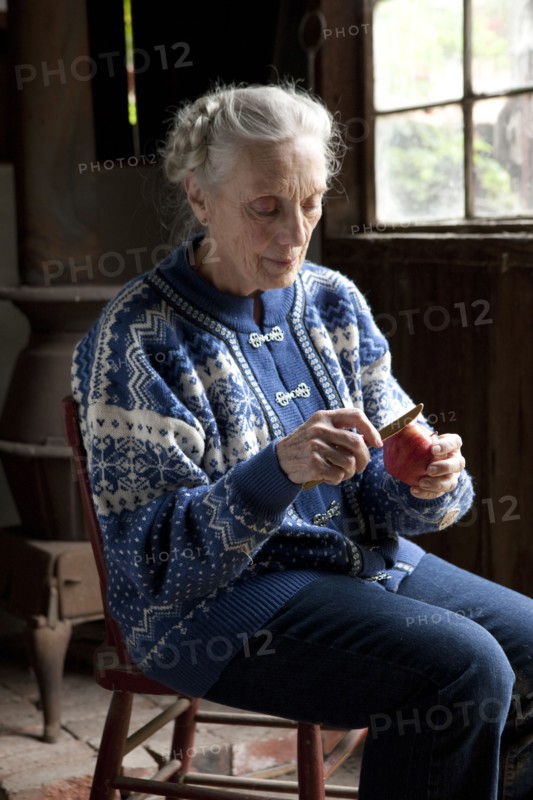Older Caucasian woman peeling fruit in living room