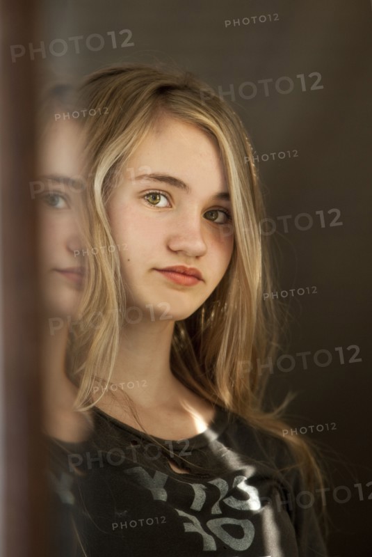 Serious teenage girl examining herself in mirror