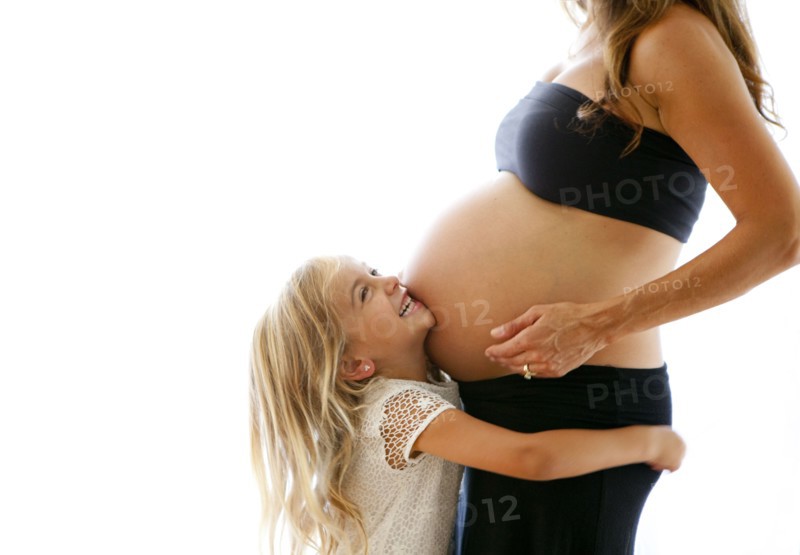 Caucasian girl hugging pregnant mother