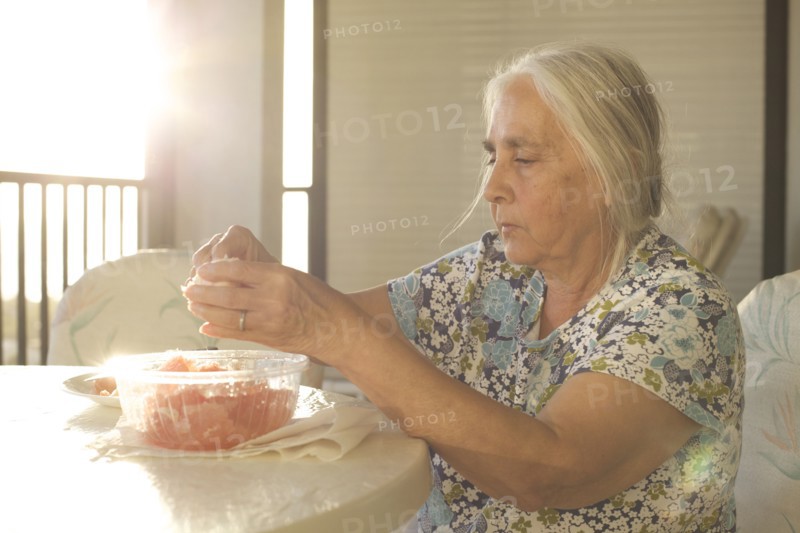 Older woman peeling fruit at table
