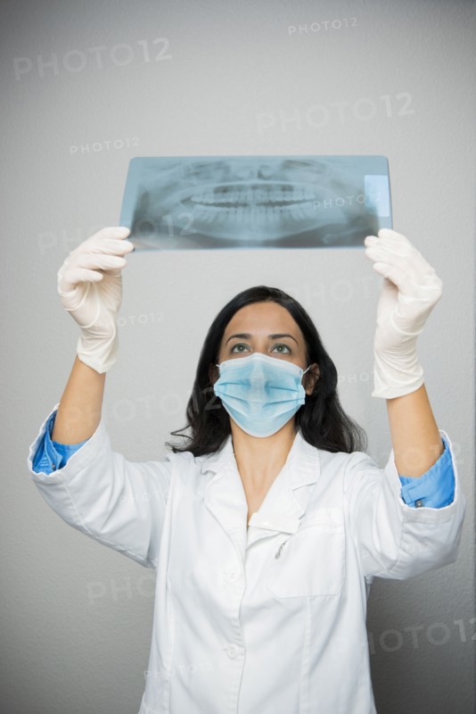 Indian dentist in face mask examining x-rays