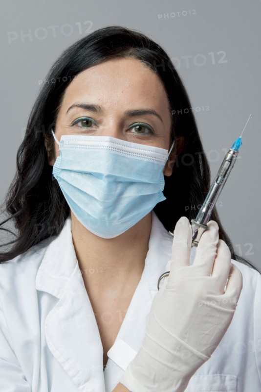 Indian dentist in surgical mask holding syringe