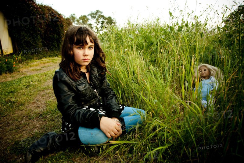 Girl playing with doll in tall grass