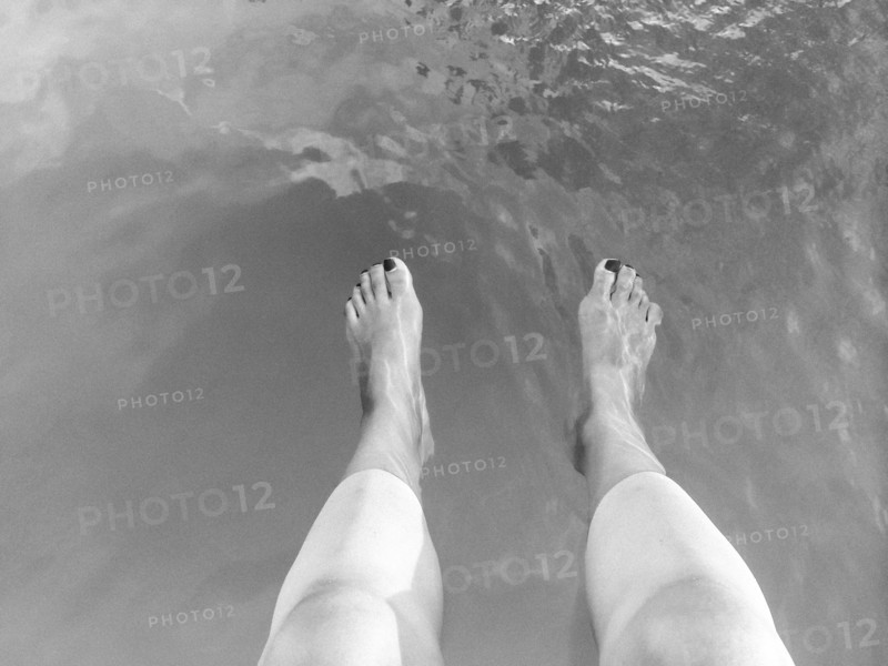High angle view of legs of woman dangling in lake