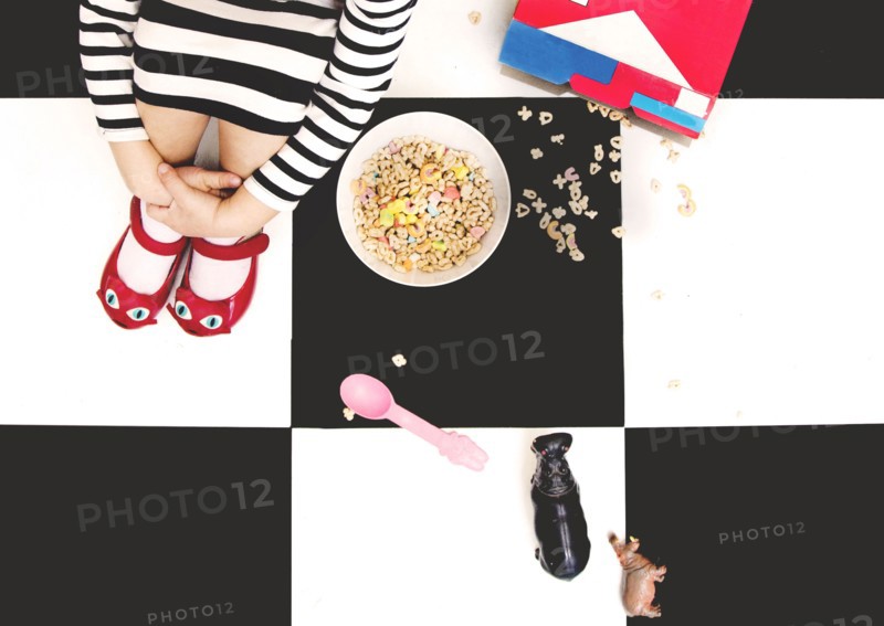 High angle view of girl spilling cereal on floor