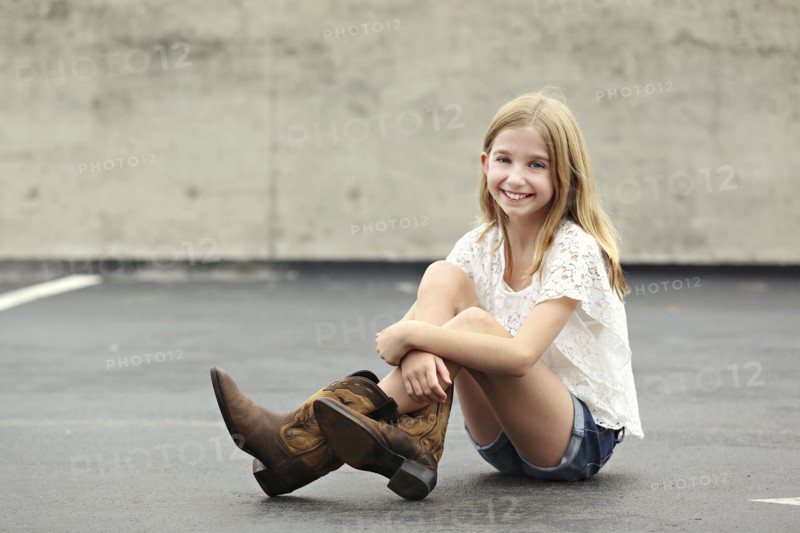 Smiling girl wearing cowboy boots in parking lot