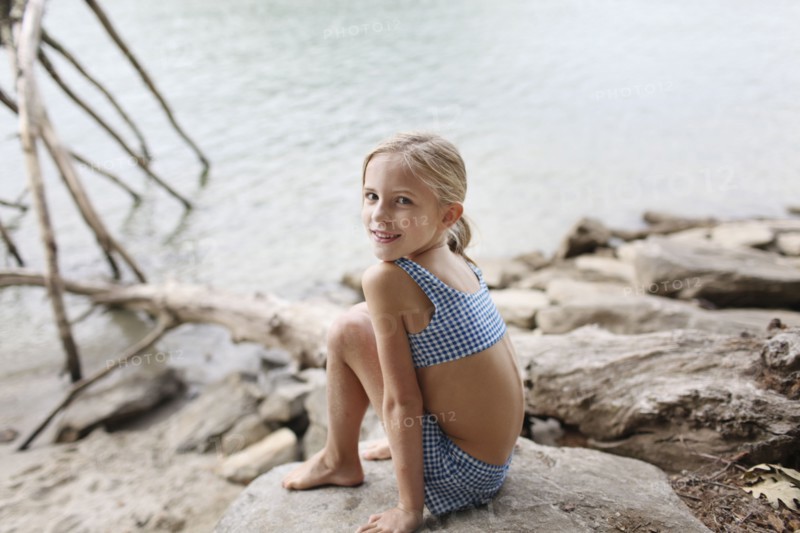 Caucasian girl in bikini sitting by remote lake