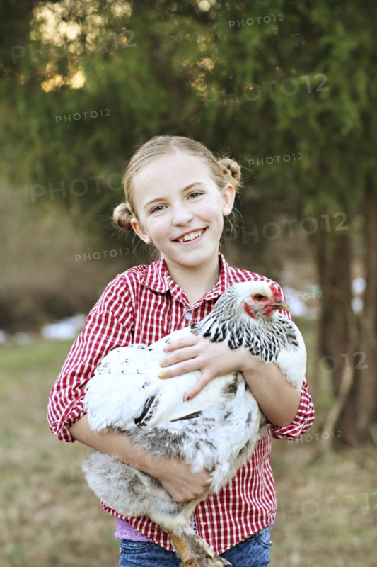 Caucasian girl holding chicken on farm