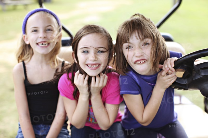 Caucasian girls making faces in golf cart