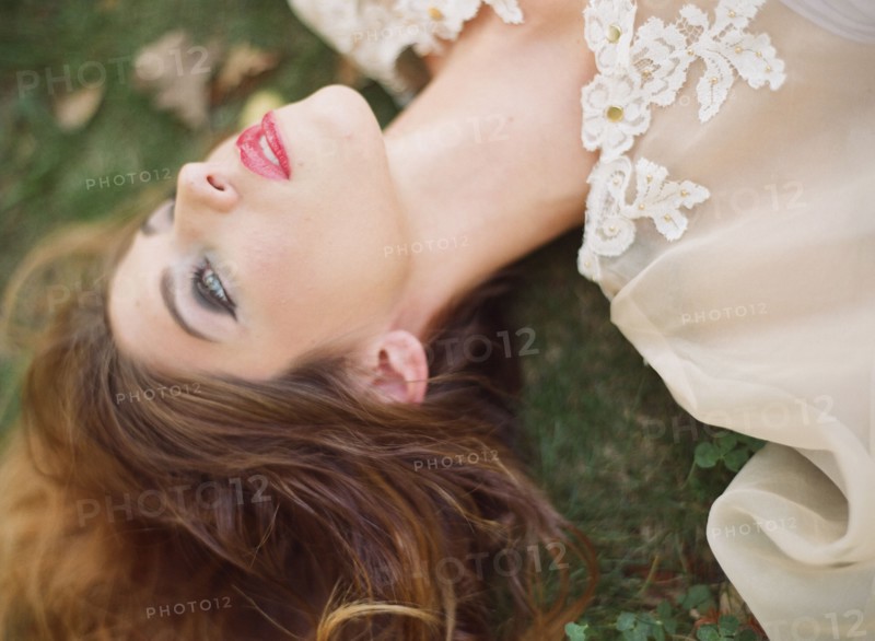 Woman in white blouse laying on lawn