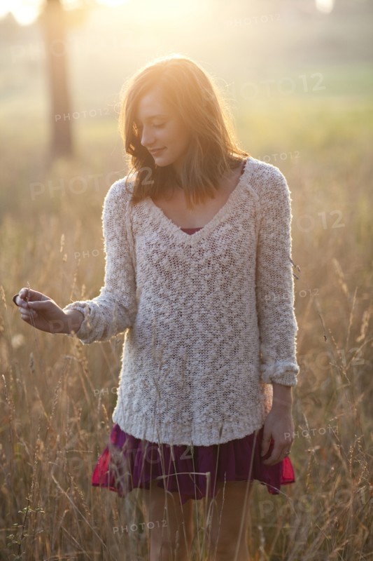Girl standing in tall grass in rural field