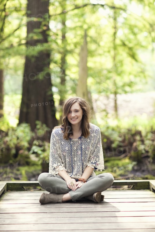 Girl sitting on wooden patio near tree