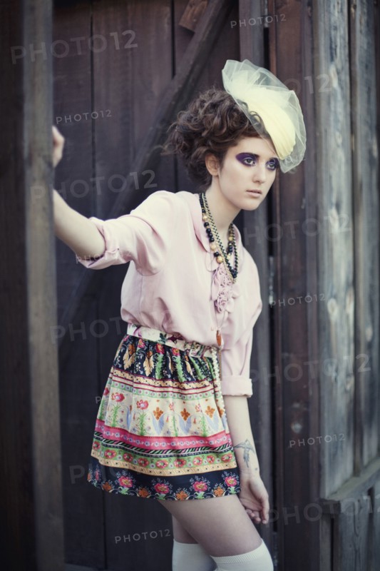 Stylish woman leaning on wooden gate