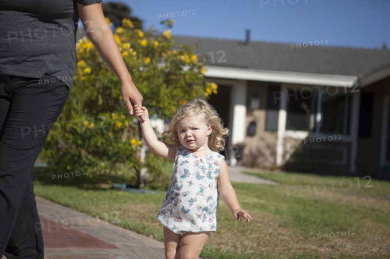 Mother and daughter walking on sidewalk