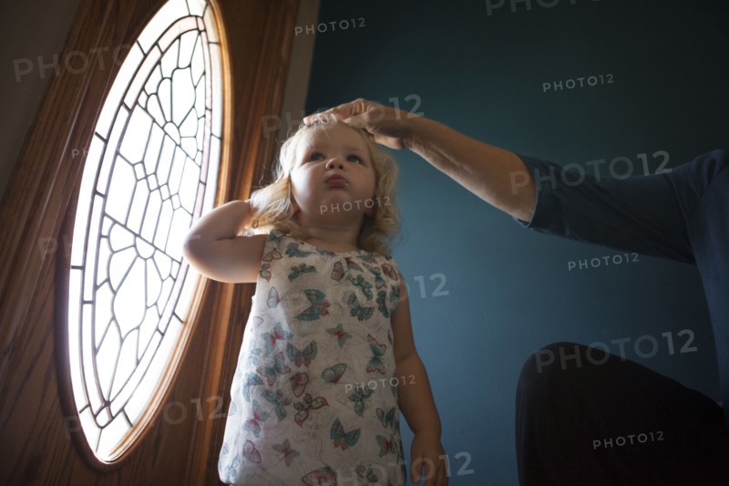 Grandmother patting granddaughter on head near door