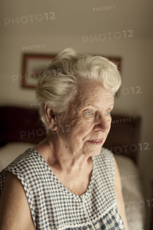 Pensive older woman sitting on bed